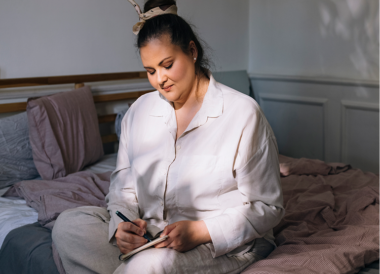 Woman writing in sleep diary